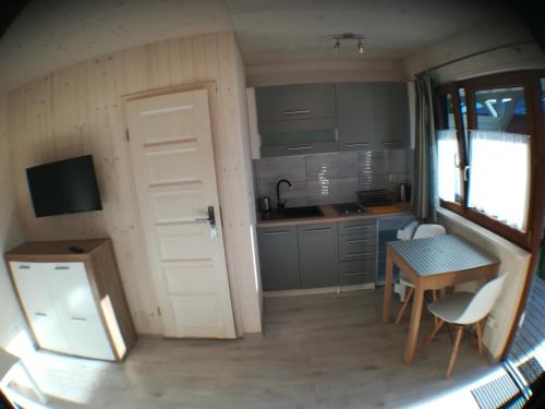een kleine keuken met een deur en een tafel en stoelen bij Domki-Apartamenty HALS in Władysławowo