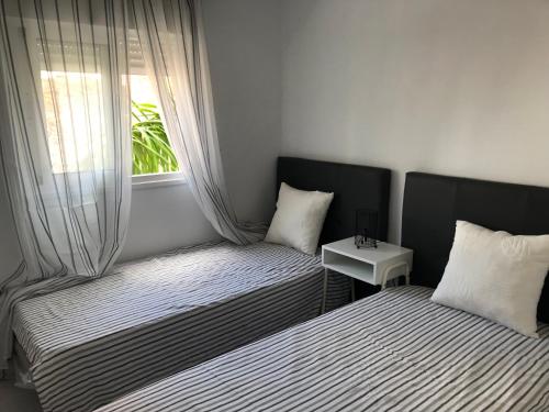 due letti in una piccola stanza con una finestra di Bubu Beach 2-A a Los Cristianos
