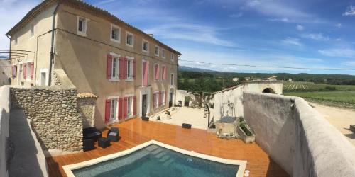 a building with a swimming pool in front of a building at Le Temps d'un Rêve in Mazan