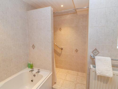 a bathroom with a shower and a tub and a sink at Rose Cottage in Darlington