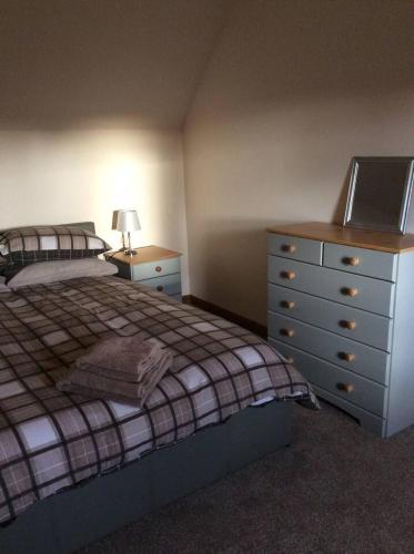 a bedroom with a bed and a dresser with a laptop on it at Cliff Cottage in Kyle of Lochalsh
