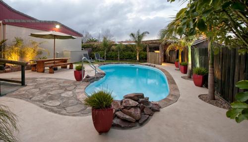 a swimming pool in a yard with a patio at Sport Of Kings Motel in Rotorua