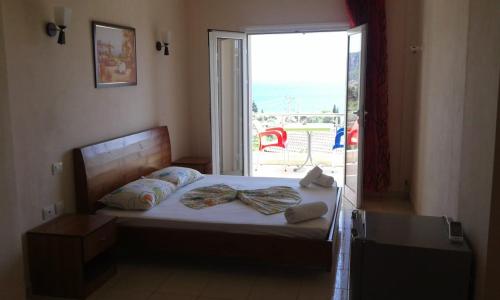 a bedroom with a bed with a large window at Oasis Drymades Hotel in Dhërmi