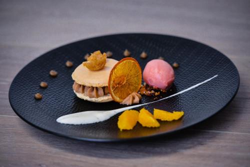 a black plate with a dessert on a table at Logis Hôtel Restaurant Le Chêne Vert in Rocher
