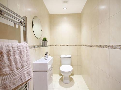 a bathroom with a toilet and a sink and a mirror at The Bay in Trearddur