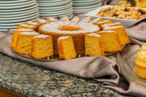 a cake on a plate on a table with plates at Hotel Itajara in Jaraguá do Sul