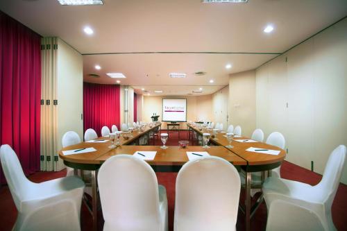 a large conference room with a long table and white chairs at favehotel MEX Tunjungan Surabaya in Surabaya