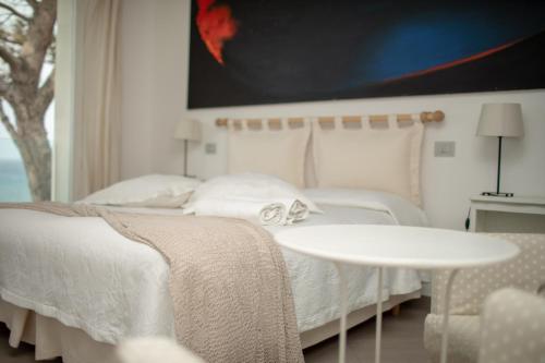 a white bedroom with two beds and a table at Il Gabbiano Relais in Stromboli in Stromboli