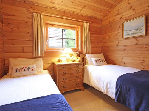 a bedroom with two beds in a log cabin at Y Berllan in Bodorgan