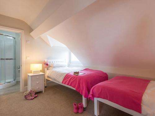 a bedroom with two beds with pink sheets at West View in Rhosneigr