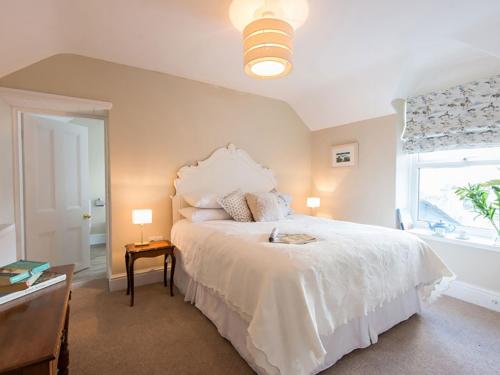 a bedroom with a white bed and a window at West View in Rhosneigr