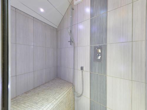 a shower with a glass door in a bathroom at Y Stabl in Criccieth