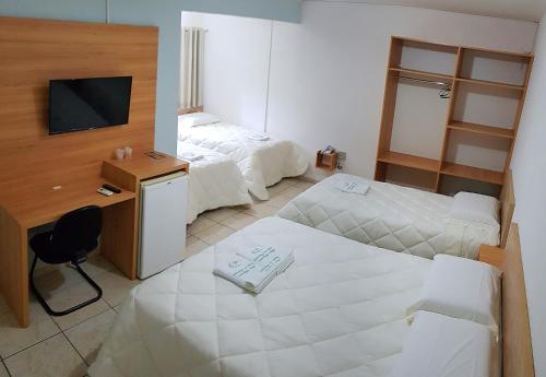 Habitación de hotel con 2 camas, escritorio y TV. en Hotel Imperador Caldas, en Santo Amaro da Imperatriz