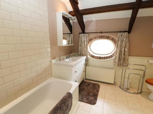 a bathroom with a tub and a sink and a window at The Groom's House in Callington