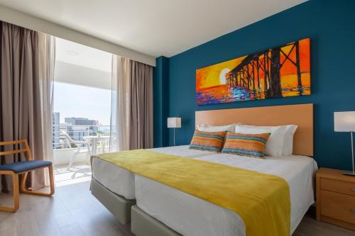 een slaapkamer met een bed met een schilderij aan de muur bij Luna Olympus in Vilamoura