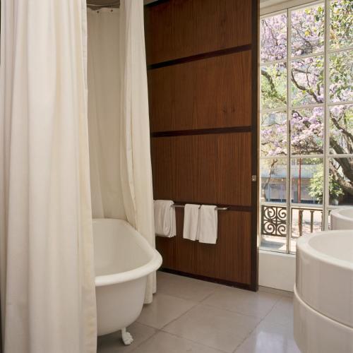 a bathroom with a tub and a toilet and a window at Condesa df, Mexico City, a Member of Design Hotels in Mexico City
