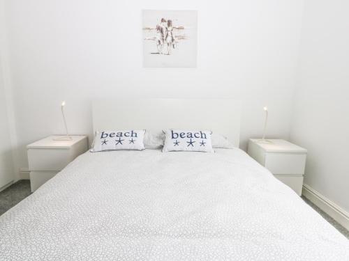 a white bedroom with a large bed with two night stands at Angel by the Sea in Bridlington