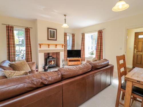 a brown leather couch in a living room with a fireplace at Gowanlea in Hexham