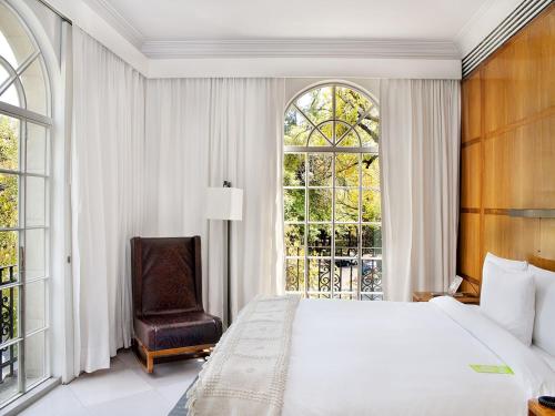 Un dormitorio con una cama y una silla y una ventana. en Condesa df, Mexico City, a Member of Design Hotels, en Ciudad de México