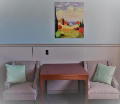 a room with two chairs and a table and a painting at Elite Hotel -Downtown Center- "Ski & Northern light Tour" "Hot Spring Tour "Long-term stay" in Whitehorse