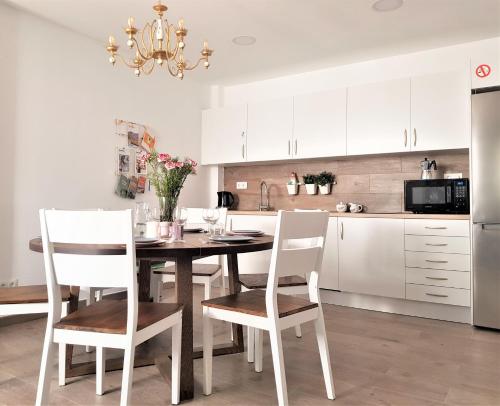 cocina con mesa de madera y armarios blancos en Immaculada Apartament Gandia, en Gandía