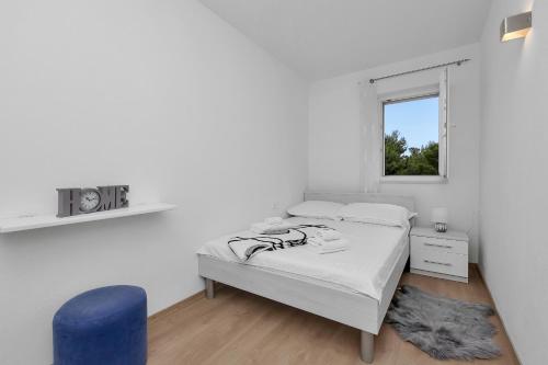 a white bedroom with a bed and a blue chair at Apartman Jug in Makarska