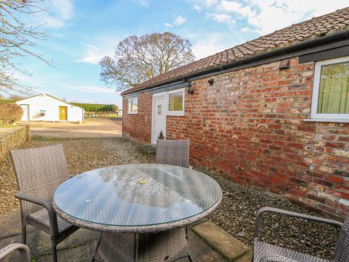 a glass table and chairs in front of a brick building at The Cottage at Manor Farm in York