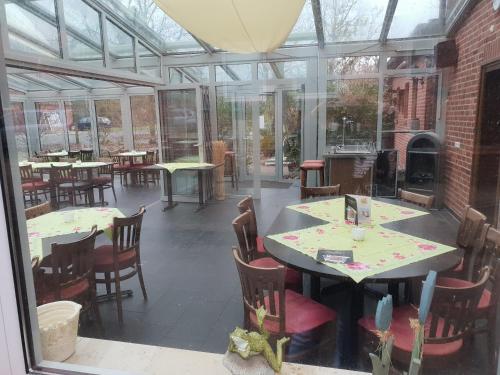 a conservatory with tables and chairs and a fireplace at Dorfkrug Grabau in Grabau