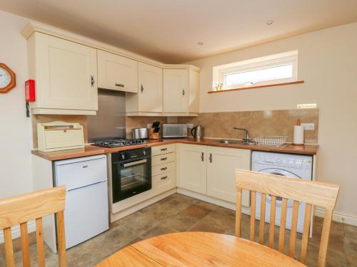 a kitchen with white cabinets and a table and chairs at The Cottage at Manor Farm in York