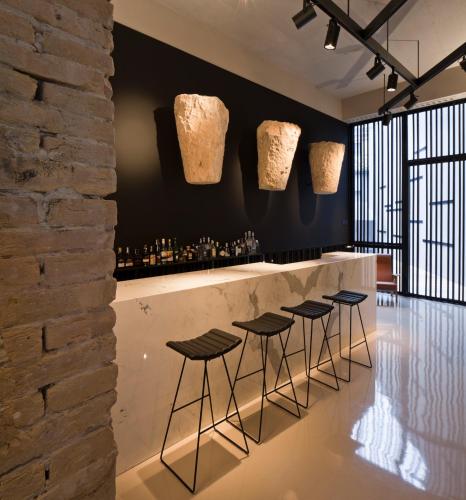a bar with stools and vases on the wall at Caro Hotel in Valencia