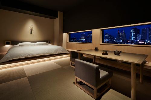 a bedroom with a bed and a desk and two windows at ONSEN RYOKAN YUEN SHINJUKU in Tokyo