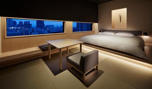 a bedroom with a bed and a table and a window at ONSEN RYOKAN YUEN SHINJUKU in Tokyo