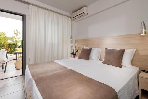 a bedroom with a large bed and a balcony at Princess Golden Beach Hotel in Chrysi Ammoudia