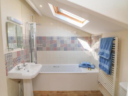 a bathroom with a sink and a bath tub at Upper Barn Cottage in Minehead