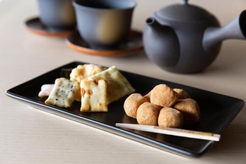 a black plate with pastries and a teapot at ONSEN RYOKAN YUEN SHINJUKU in Tokyo