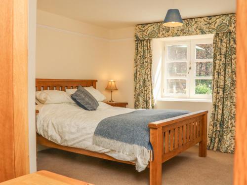 a bedroom with a bed and a window at Upper Barn Cottage in Minehead