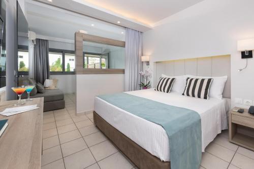 a bedroom with a large bed and a living room at Princess Golden Beach Hotel in Chrysi Ammoudia