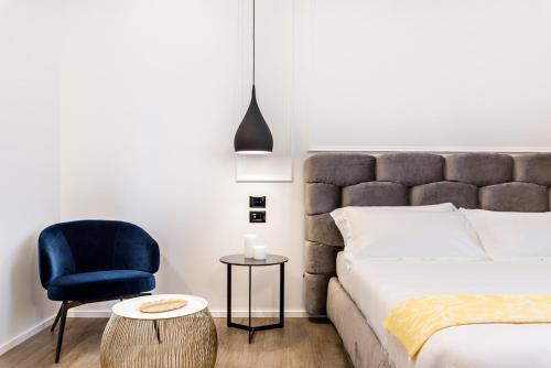 a bedroom with a bed and a blue chair at La Spezia by The First - Luxury Rooms & Suites in La Spezia