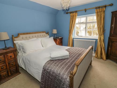 a bedroom with a bed with blue walls and a window at Fountain View Cottage in Upper Heyford