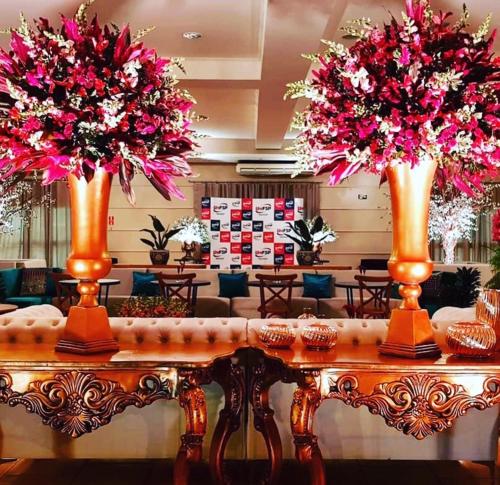 a table with two vases with pink flowers on it at Villa Verde Hotel in Avaré
