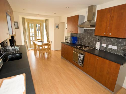 a kitchen with wooden cabinets and a dining room at Bwthyn Llechen in Porthmadog