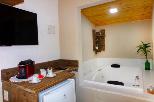 a bathroom with a tub and a tv and a sink at Pousada Polessas in Visconde De Maua