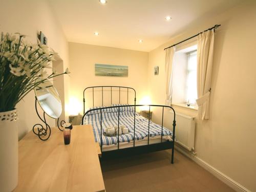 a bedroom with a bed and a vase of flowers at Bwthyn Llechen in Porthmadog