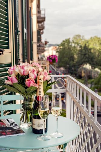 a table with two glasses and a bottle of wine and flowers at La Spezia by The First - Luxury Rooms & Suites in La Spezia