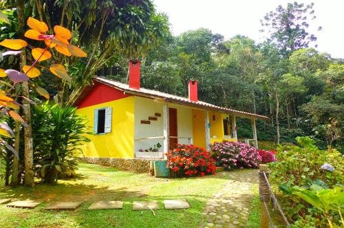 a small yellow and red house in a garden at Pousada Polessas in Visconde De Maua