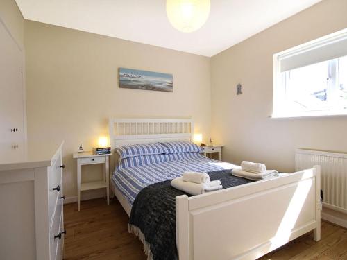 a bedroom with a bed and a desk and a window at Bwthyn y Mor in Porthmadog