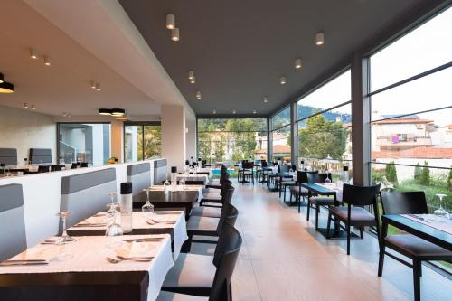 a restaurant with tables and chairs and large windows at Princess Golden Beach Hotel in Chrysi Ammoudia