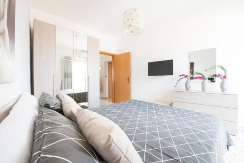 a white bedroom with a bed and a tv at Casa Vacanze La Meridiana in Modica