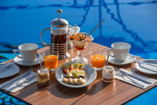 a table with a breakfast of fruit and juice at Elounda Heights (Adults Only) in Elounda