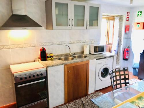 a kitchen with a sink and a washing machine at Casa da Quinta da Prelada Simão partie basse in Celorico de Basto